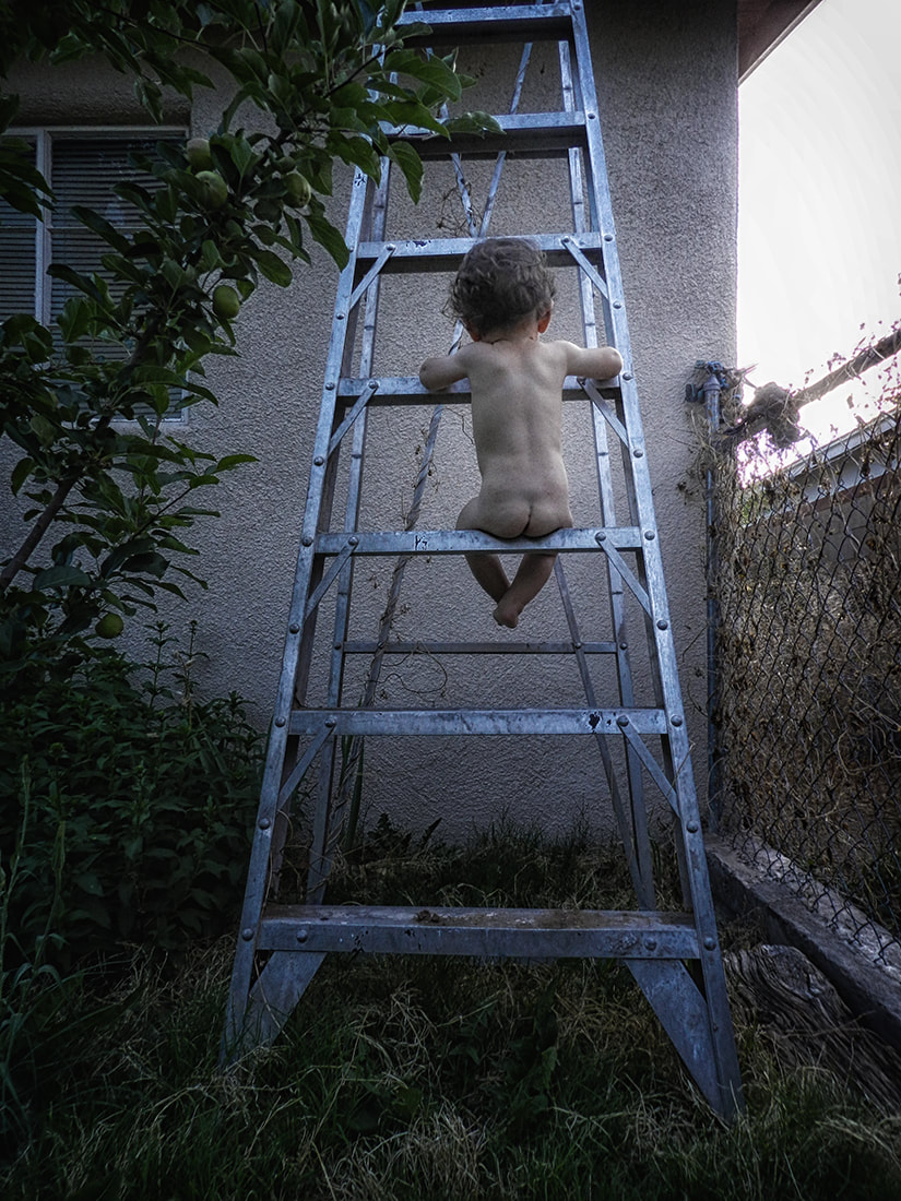 small child sits naked on a ladder