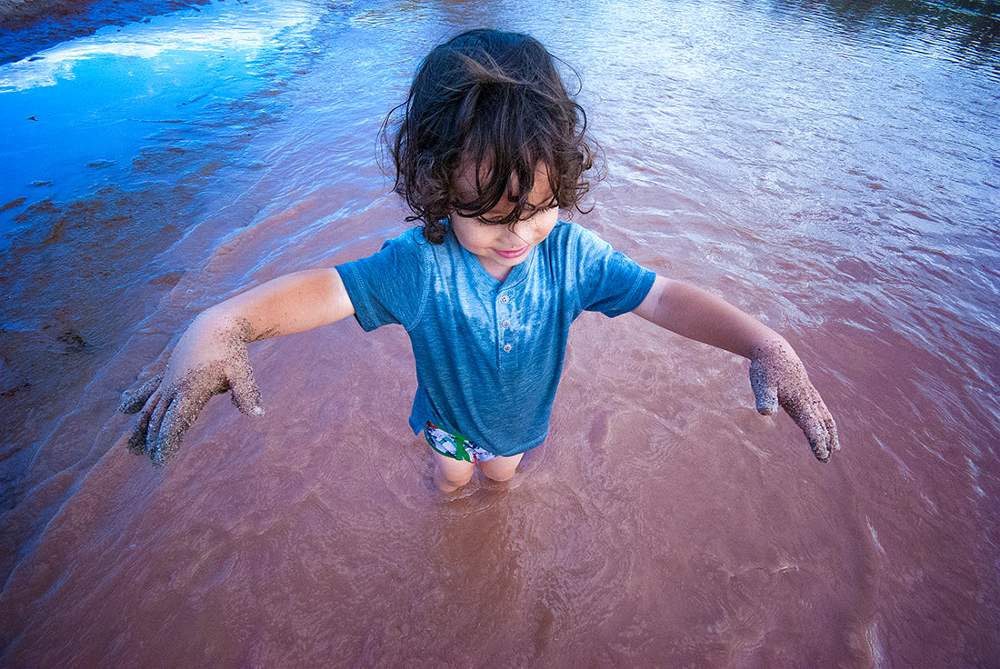 child plays in muddy river