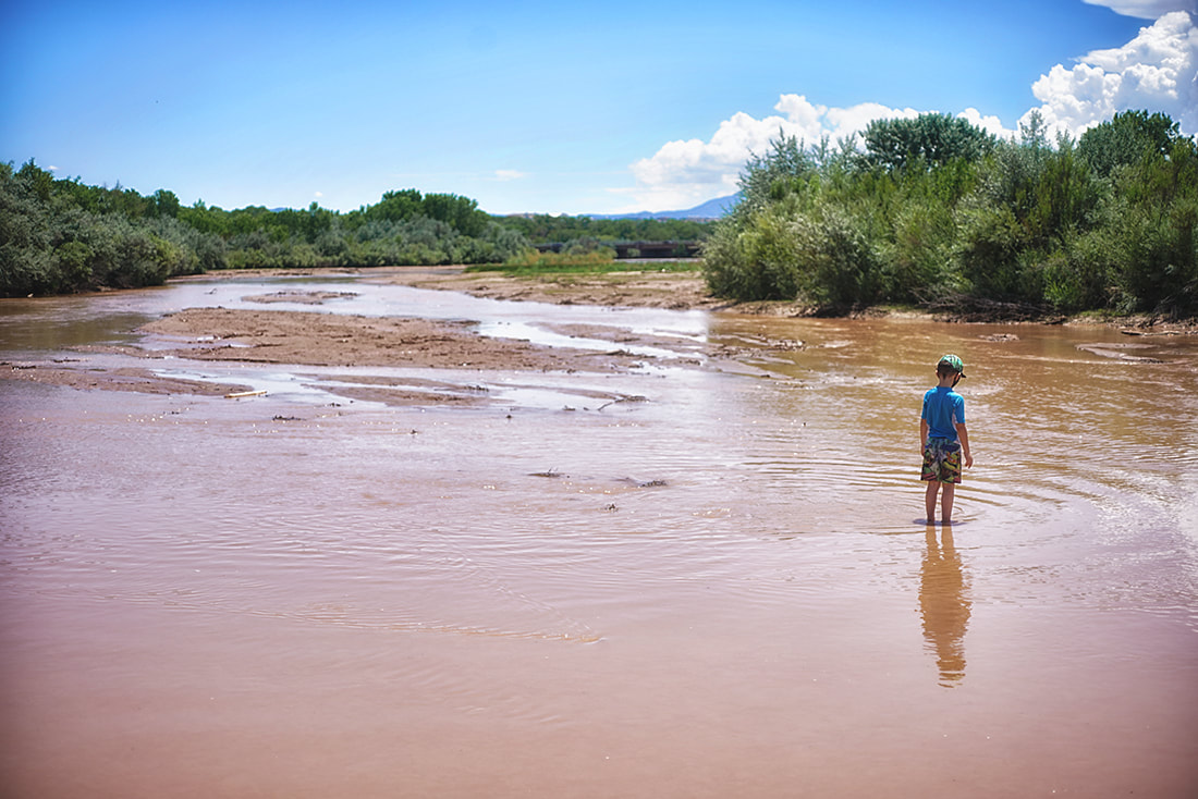 boy plays in shallow muddy rio grande